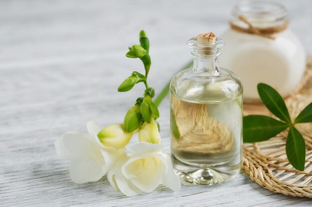 Martwa natura w spa z butelką perfum i olejku aromatycznego otoczona kwiatami frezji na jasnej powierzchni