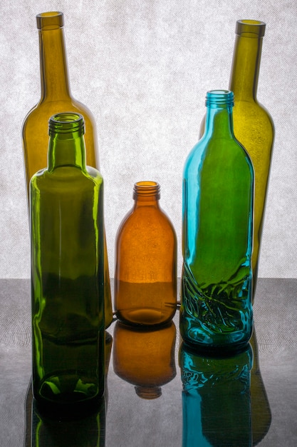 Zdjęcie martwa natura z pięcioma kolorowymi butelkami na szarym tle