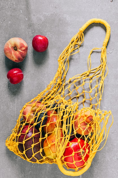 Zdjęcie martwa natura z żółtą biodegradowalną torbą na zakupy z surowymi owocami