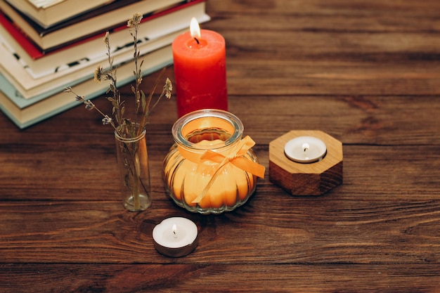 Martwa natura ze skórkami Pomarańczowa świeca aromatyczna w figurowym świeczniku z kokardą i książkami w tle