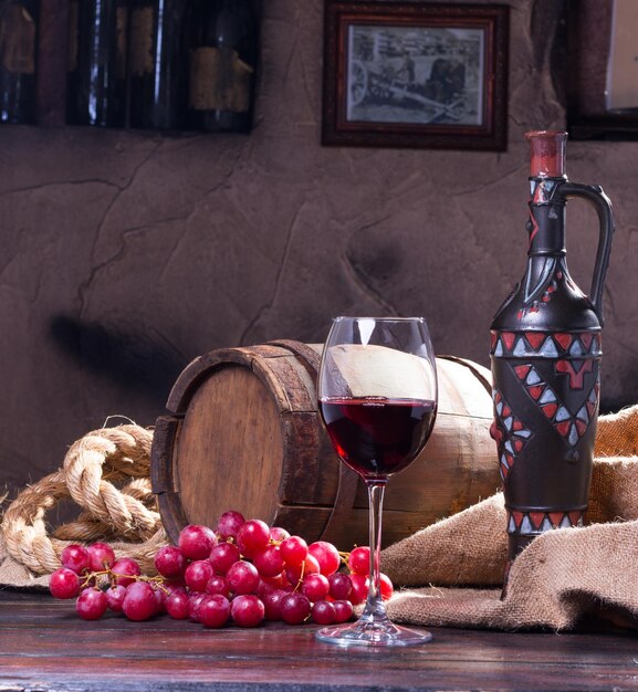 Zdjęcie martwa natura ze szkła butelki wina i winogron na oryginalnym tle