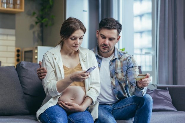 Martwienie się Młoda kobieta w ciąży z rodziną trzymającą kartę kredytową i telefon Czek nie rozumiem Zadzwoń do banku