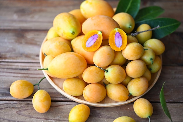 Maryjne owoce śliwki i liście w talerzu na drewnianym tle owoców tropikalnych Nazwa w Tajlandii Sweet Yellow Marian Plum Maprang Plango lub Mayong chid