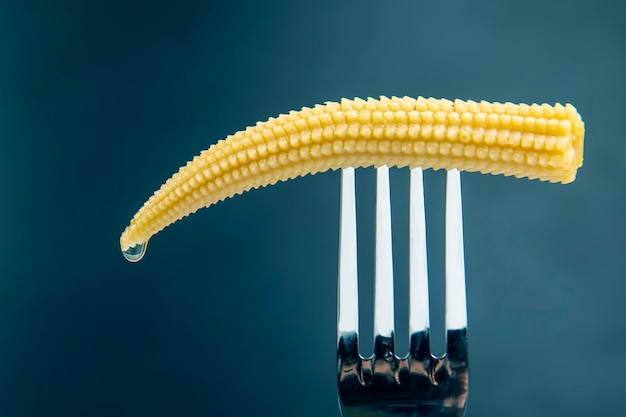 Zdjęcie marynowana kukurydza na zbliżenie widelec na ciemnym tle