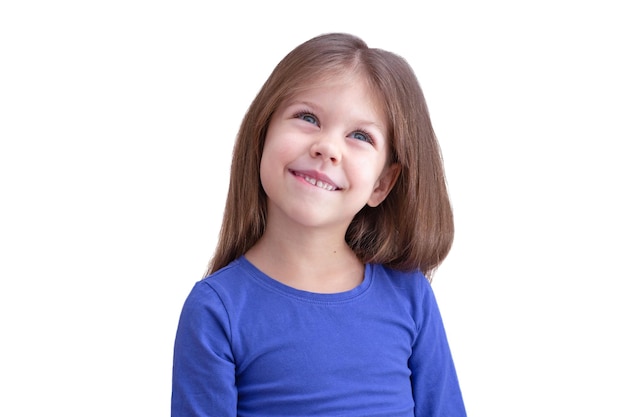 Marzy uśmiechający się szczęśliwy gryzienie wargi dziecko na białym tle patrząc w górę pasa w górę kaukaska dziewczynka 5 lat w kolorze niebieskim
