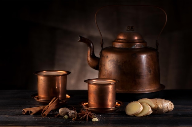 Masala chai w zabytkowym miedzianym czajniczku i filiżankach przypraw i pikantnych