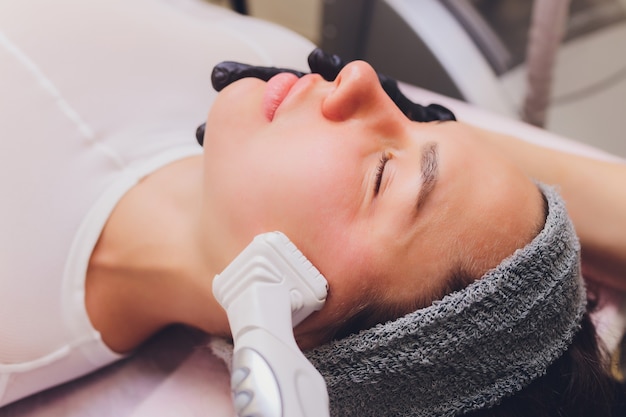 Zdjęcie masaż drenaż limfatyczny proces aparatem lpg. kosmetyczka-terapeutka wykonuje odmładzający masaż twarzy.