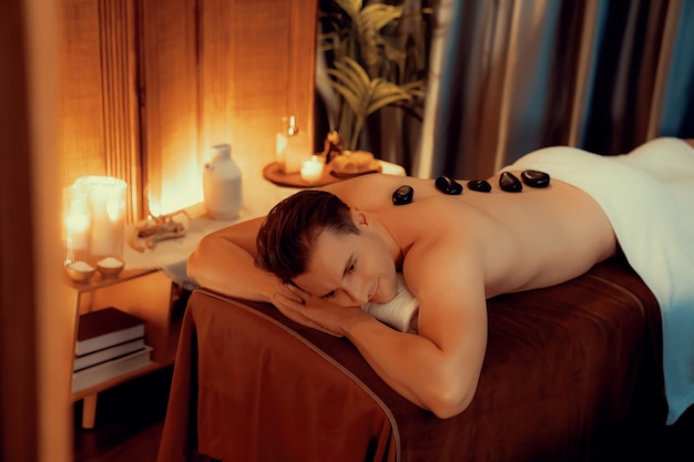 Masaż gorącymi kamieniami w salonie spa w luksusowym kurorcie z ciepłym światłem świecy