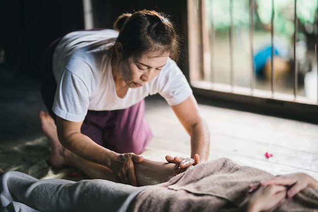 Masaż i spa relaksujące leczenie zespołu biurowego za pomocą tradycyjnego masażu tajskiego gorącym kamieniem Masażystka azjatyckich wykonująca masaż stóp leczyć stres dla kobiety