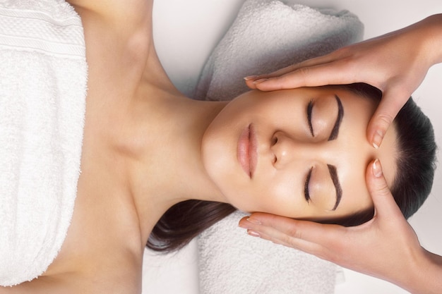 Masaż twarzy Zbliżenie młodej kobiety podczas masażu spa w salonie pięknościSpa skin