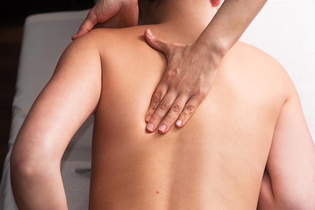 Masażysta masuje plecy i łopatki młodej kobiety na stole do masażu Koncepcja zabiegów spa masażu Zbliżenie