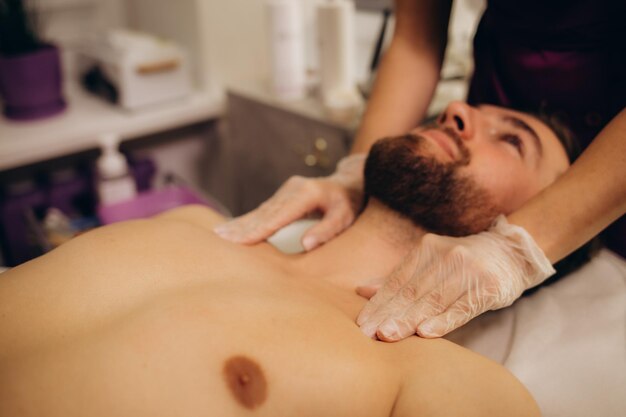 Zdjęcie masażysta robiący masaż szyi młodemu, zamożnemu, białemu sportowcowi w ciemnym pokoju salonu spa. zdjęcie wysokiej jakości.
