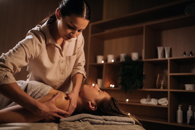 Masażystka masuje ciało kobiecie w centrum spa Profesjonalny masażysta masuje ramię dziewczyny leżącej w centrum spa