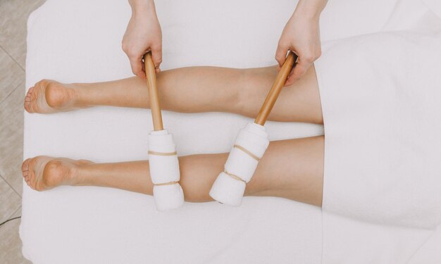 Zdjęcie masażystka wykonuje masaż nóg i ud kijami bambusowymi