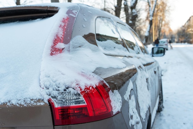Maska i drzwi samochodu pokryte śniegiem i lodem po opadach śniegu Zaparkowane samochody pokryte śniegiem Wielkie mrozy i dużo śniegu w mieście Problemy na zimowych śliskich drogach