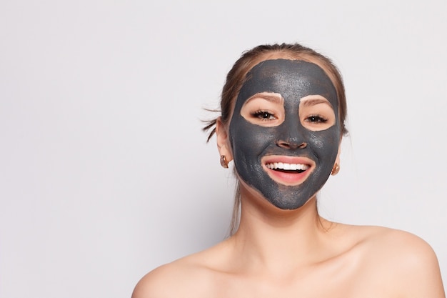 Zdjęcie maska na twarz kobiety. portret pięknej dziewczyny usuwanie czarnej maski kosmetycznej ze skóry twarzy. zbliżenie atrakcyjna młoda kobieta z naturalnego makijażu i maski skórki kosmetycznej na twarzy. wysoka rozdzielczość