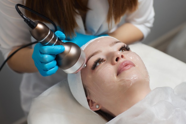 Zdjęcie maska przeciwstarzeniowa led do pielęgnacji skóry twarzy w spa w zwolnionym tempie kobieta leży na kanapie w specjalnej masce nowoczesne technologie urody i zdrowia