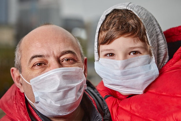 Maski medyczne mężczyzny i małego chłopca na twarzach jako ochrona przed koronawirusem.