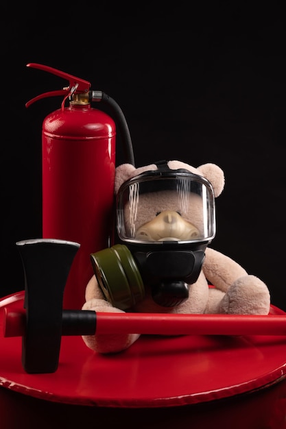 Maskotką straży pożarnej jest miś w masce gazowej z gaśnicą i czerwoną siekierą w dymie na ciemnym tle