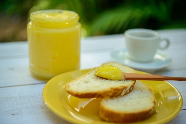 Masło Ghee Z Krojonym Chlebem Na żółtym Talerzu Na Stole śniadaniowym Ze Szklanym Słoikiem Masła I Filiżanką