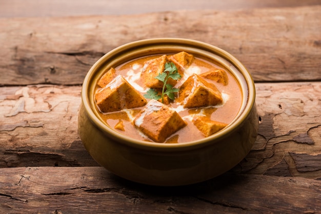 Masło Paneer Masala znane również jako Panir makhani lub makhanwala. podawane w misce ceramicznej lub terakotowej ze świeżą śmietaną i kolendrą. selektywne skupienie