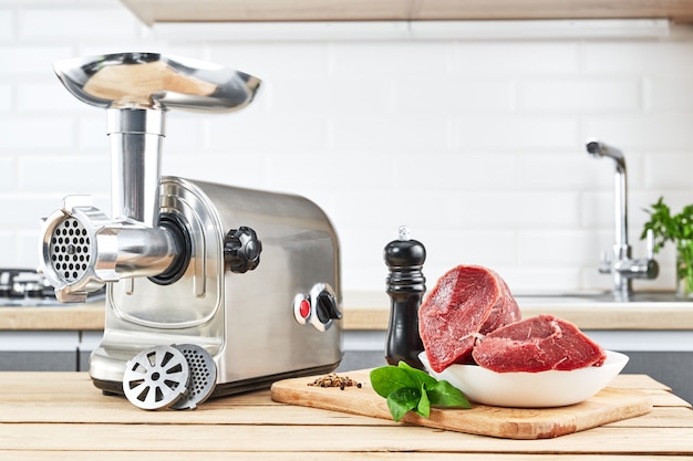 Zdjęcie maszynka do mięsa z świeżym mięsem na drewnianym stole w kuchennym wnętrzu