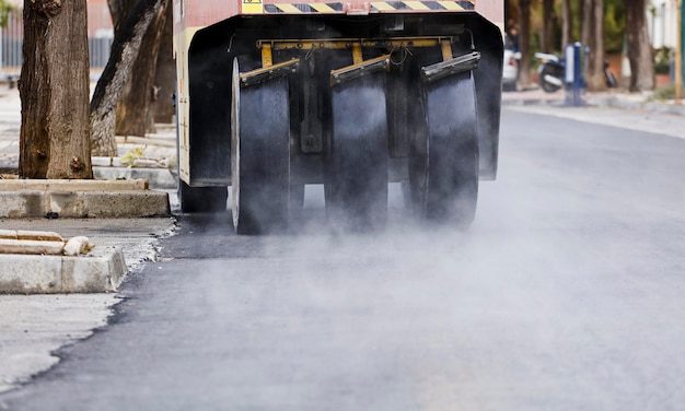maszyny do układania asfaltu z dużymi kołami, opary dymu ze świeżo wykonanego gorącego betonu