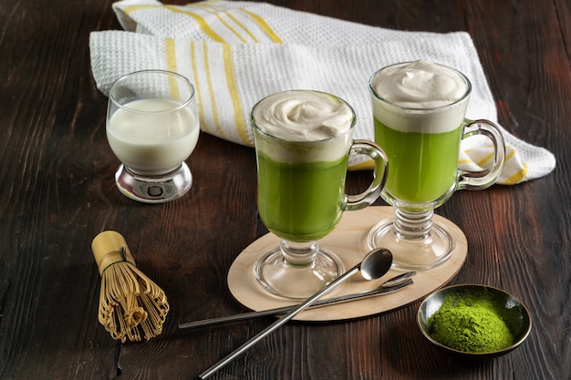 Matcha latte z kremową pianką w szklankach i bambusową trzepaczką