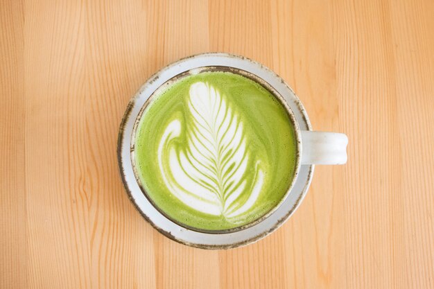 Zdjęcie matcha zielonej herbaty latte art na drewnianym stole