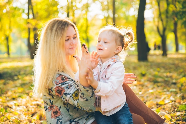 Mather z małą córeczką bawiącą się w jesiennym miejskim parku miejskim