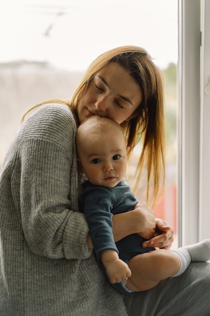 Matka Bawi Się Z Synkiem W Domu Przy Oknie. Szczęśliwe Niemowlę I Mama.