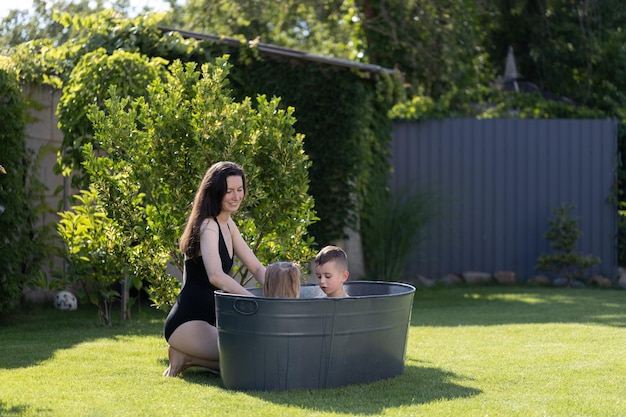 Matka bawiąca się z dziećmi w wannie na świeżym powietrzu na podwórku w okresie letnim