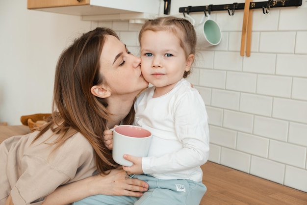 Matka całuje córkę w domu w kuchni śniadanie Mała dziewczynka patrzy na kamerę