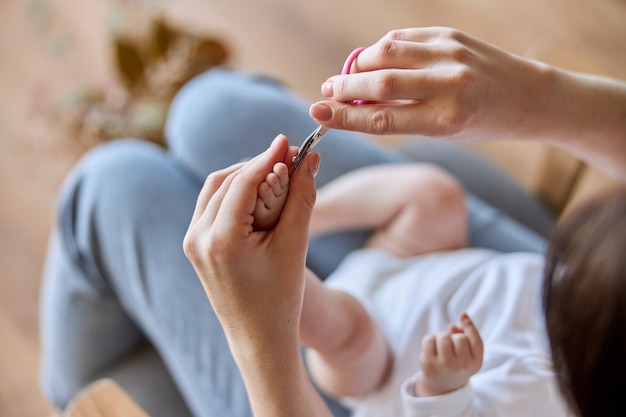 Matka cięcia paznokci na nodze noworodka. Ścieśniać. Widok z góry. Pojęcie macierzyństwa i opieki nad dzieckiem