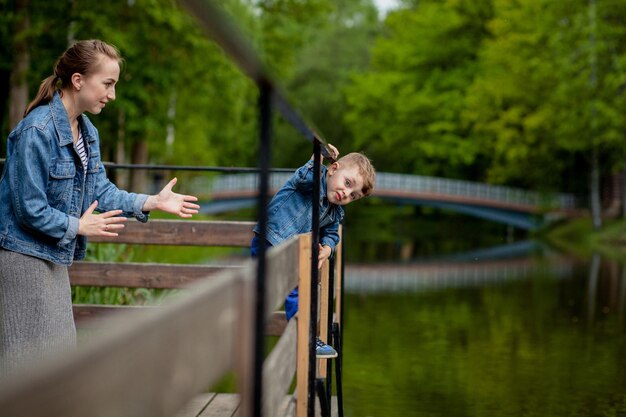 Matka doświadcza, że dziecko wpadnie do wody Mały chłopiec wspina się po balustradzie mostu w parku Groźba utonięcia Niebezpieczeństwo dla dzieci