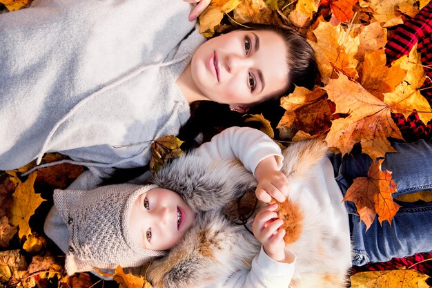 Matka i córka leżą na jesiennych liściach