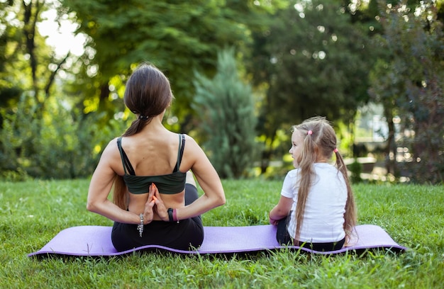 Matka i córka medytują ćwicząc jogę razem na matce w parku Macierzyństwo Spędzanie czasu Mama Trener zdrowa koncepcja rodziny