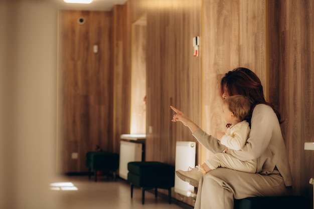 Matka i córka na korytarzu szpitala oglądają filmy na smartfonie i tabletie
