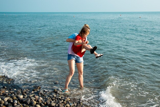 Matka i córka na plaży skaczą po falach i dobrze się bawiąWakacje letnie Rodzinne wakacje