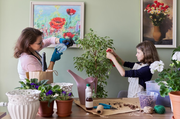 Matka i córka opieka nad dzieckiem razem dla domu kwiat w doniczce, dziewczyna kropi sprayem na roślinę. Hobby i wypoczynek, opieka, rodzina, roślina doniczkowa, koncepcja przyjaciół doniczkowych w domu