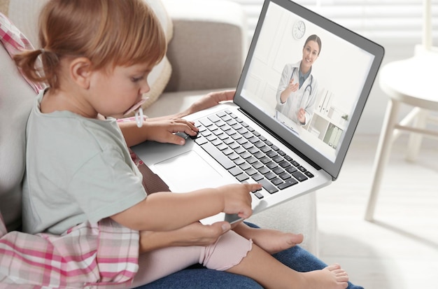 Matka i córka po konsultacji online z pediatrą za pośrednictwem laptopa na kanapie w domu