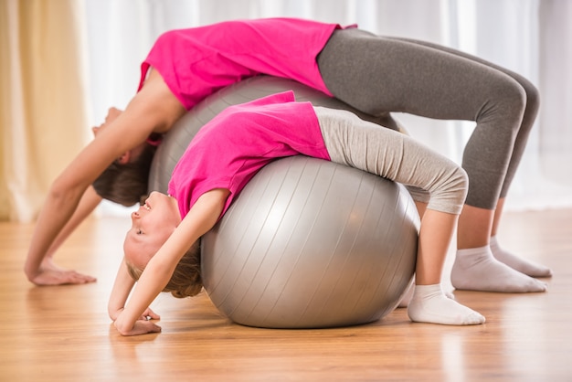 Matka i córka robi ćwiczenia fizyczne na piłkę fitness