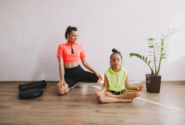 Matka i córka robią medytację i jogę, uprawiając sport i fitness w domu