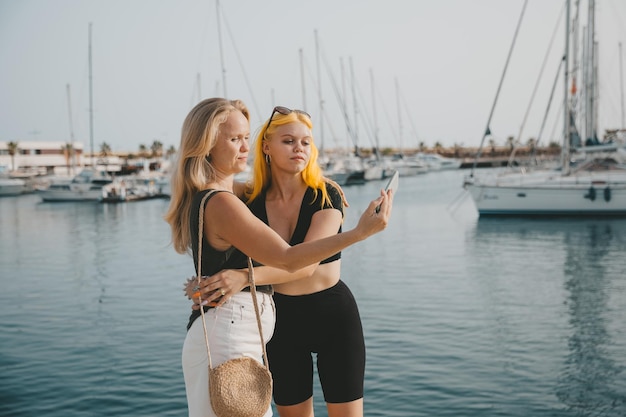 Matka i córka robią sobie selfie na tle morza i jachtów