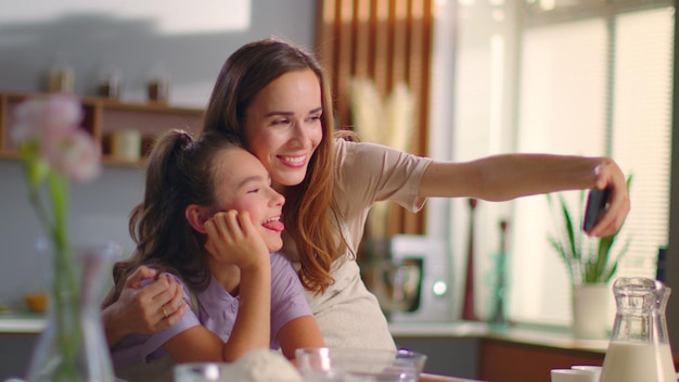 Matka i córka robienia zdjęć selfie na smartfonie w kuchni