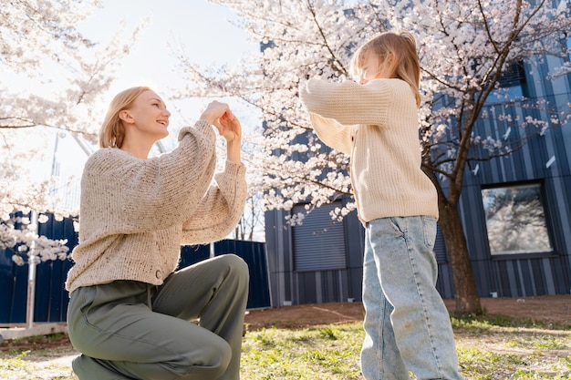 Matka i córka są szczęśliwe razem w kwitnących drzewach w ogrodzie przed domem Szczęśliwego Dnia Matki
