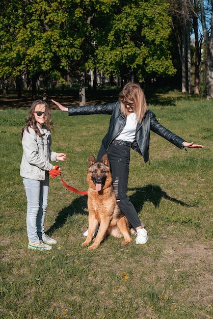 Matka i córka spacerują po parku z owczarkiem niemieckim