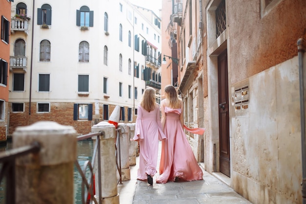 Matka i córka spacerują w słonecznej Wenecji w miękkich różowych sukienkach Koncepcja aktywnego stylu życia