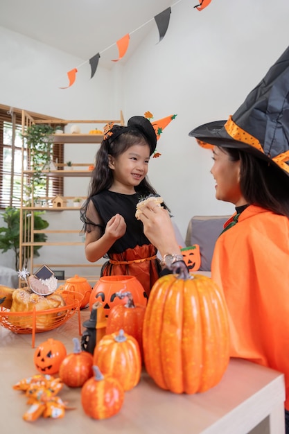 Zdjęcie matka i córka świętują halloween, jedzą razem ciasto w domu.