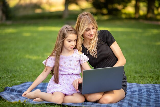 Matka i córka szczęśliwie patrzą na laptop w parku